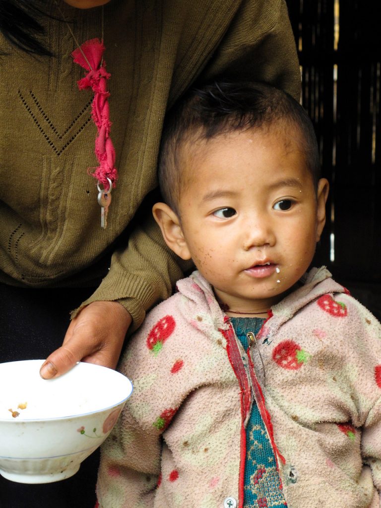 Carnets de voyage en Birmanie 2010. A proximité de la ville de Kalaw, dans l'état Shan, une mère portant les clés de sa maison à son cou dans un village de montagne donne à manger à son enfant sur la route du lac Inle. Photo Mathieu THOMASSET
